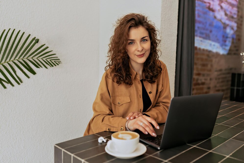 spectacular-charming-lady-with-curls-wearing-brown-shirt-sitting-cafe-with-coffee-working-laptop-remote-sunny-warm-day_291650-2688